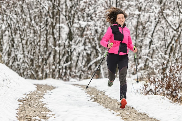 Girl runs with sticks in hand on dirt road in winter