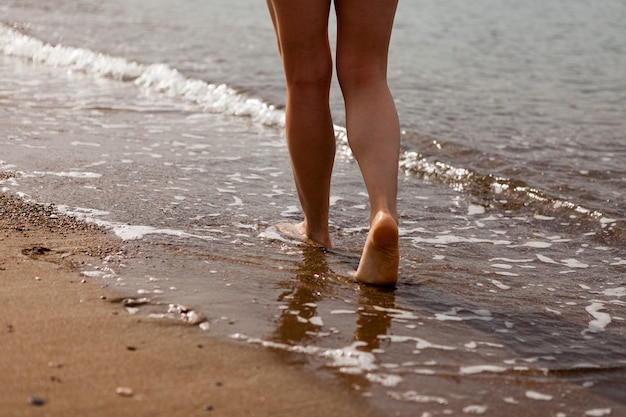 A girl's feet walking on the sand along the sea coast. Sand and sea water. The girl walks on the sand. Stop close-up.