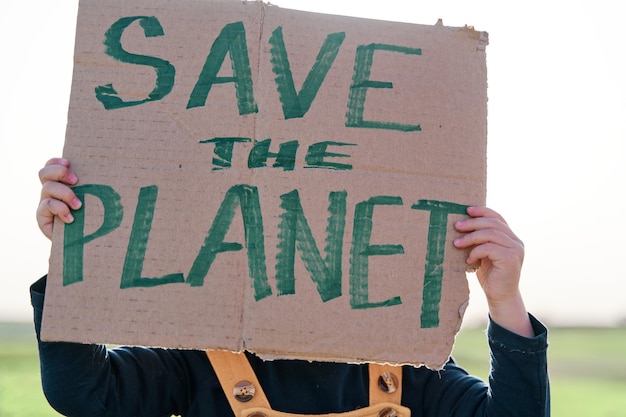 Photo girl's hand holding a cardboard sign that says save the planet