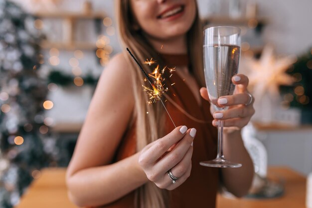 Girl's hand holding a glass of champagne and a sparkler preparing for the celebration