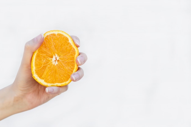 Photo girl's hand holds half a juicy orange on white