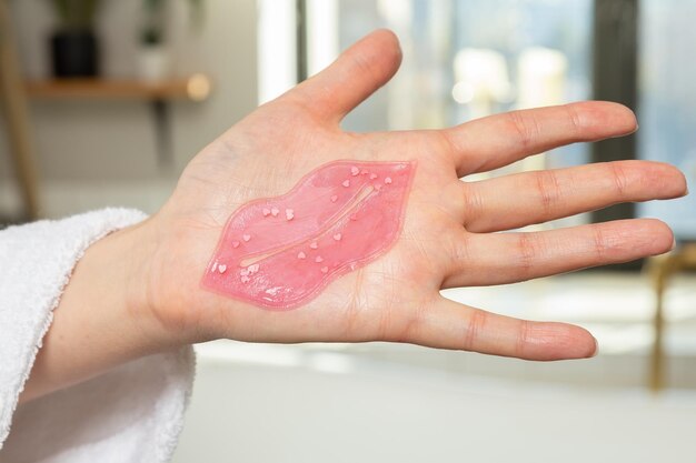 a girl's hand holds a lip patch, a lip patch, women's facial bath treatments