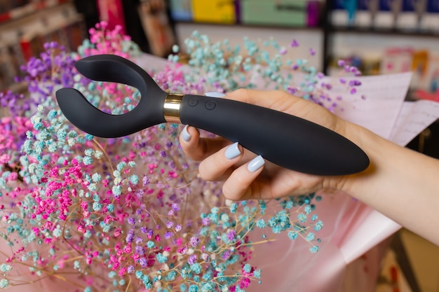 Girl's hand holds a massager for sex. Vibrator for masturbation. Dildo for vaginal and clitoral stimulation. Image for sex shop.