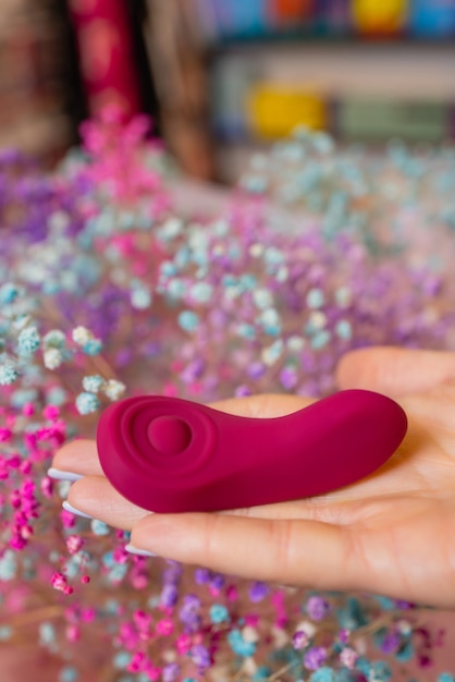 Girl's hand holds a massager for sex. Vibrator for masturbation. Dildo for vaginal and clitoral stimulation. Image for sex shop.