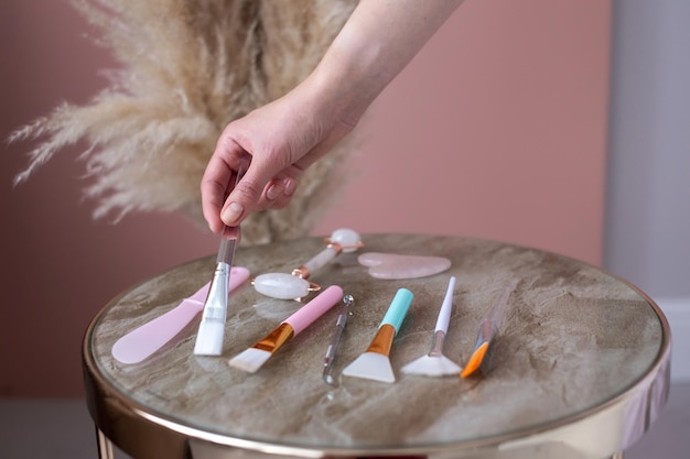 The girl's hand picks up a body care brush from a table with a lot of tools