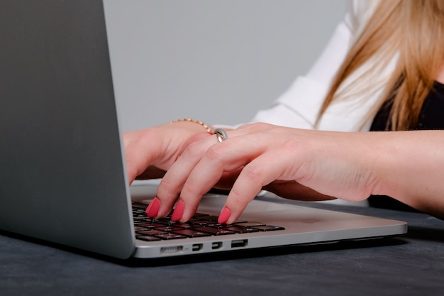 The girl's hand prints the text on the keyboard of the laptop. A freelancer's concept.