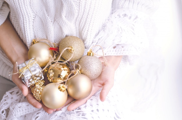 Le mani della ragazza che tengono le palle d'argento e dorate di natale