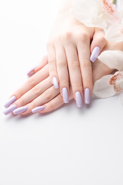 Girl's hands with delicate purple manicure and orchid flowers