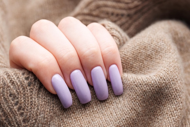 Le mani della ragazza con una morbida manicure viola