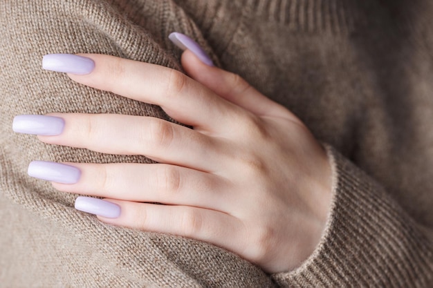 Руки девушки с нежно-фиолетовым маникюром