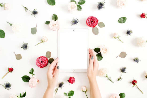 Photo girl's hands with tablet on floral frame with red and beige rose flower buds on white