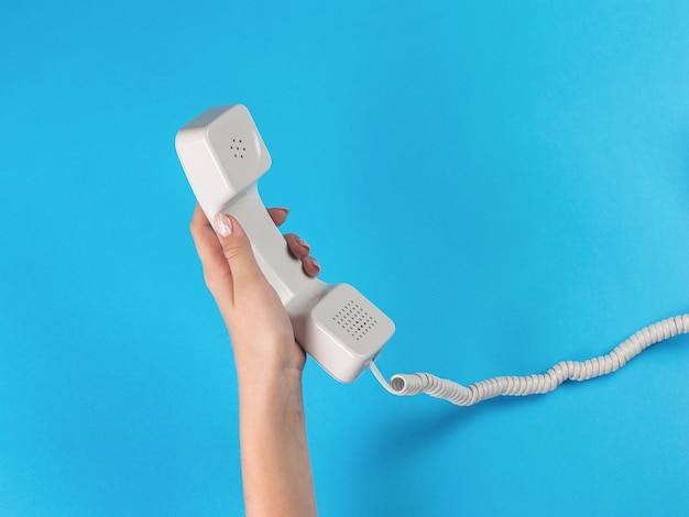 The girl's left hand holds a white telephone receiver on a wire