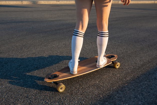  Girl's legs are on the longboard, she rides. Walk on the logboard at the weekend. Girl's feet stand on the board. . Copyspace