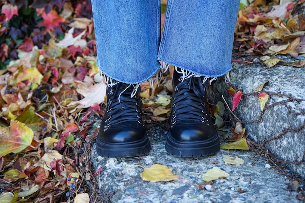 Girl's legs on the stairs in the autumn park in black boots
closeup autumn concept