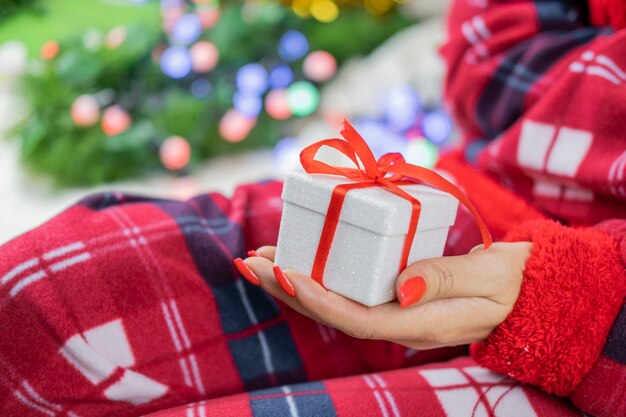 a girl in santa claus pajamas holding a box of surprise gift