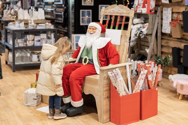 Foto ragazza e babbo natale in un negozio