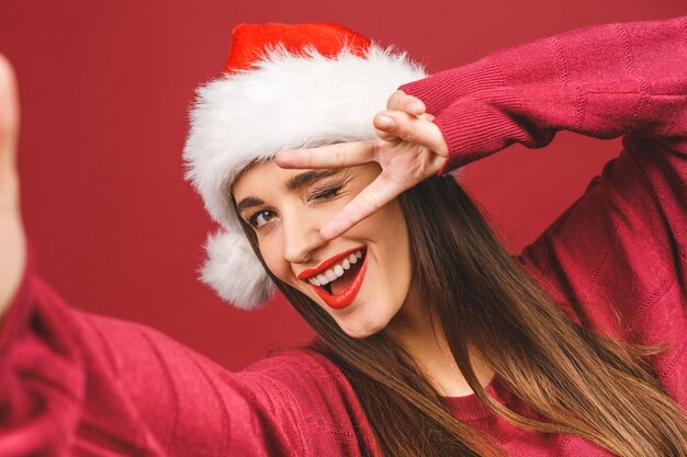 Girl in Santa costume smiling and taking selfie on mobile phone