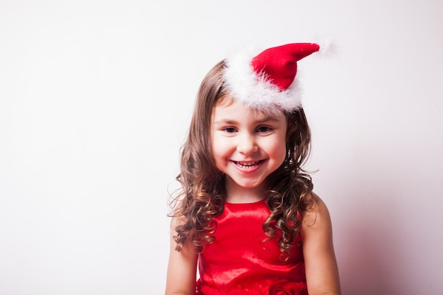 Girl in Santa hat headband over white wall, copy space