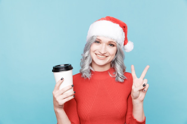 Girl in the santa's hat with a cup of coffee