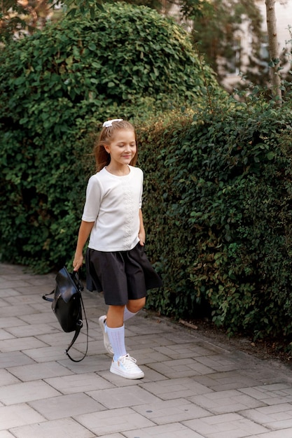 a girl in a school uniform walks in the park