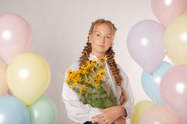 Girl schoolgirl, high school student with flowers and balls on a white background