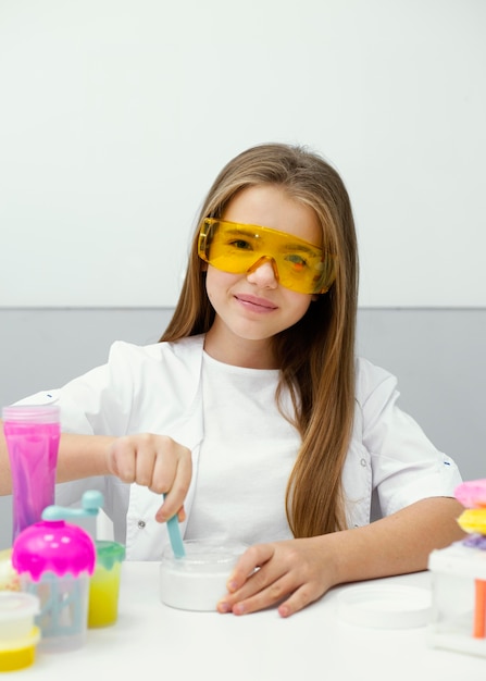 Foto scienziato della ragazza che ha divertimento facendo la melma in laboratorio