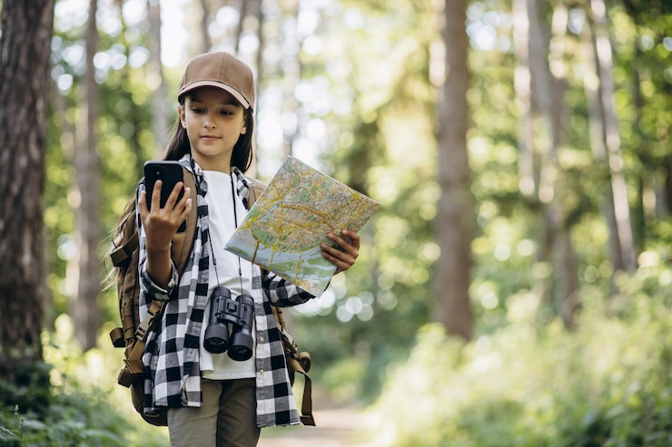 Photo girl scout looking on the map and phone in the woods