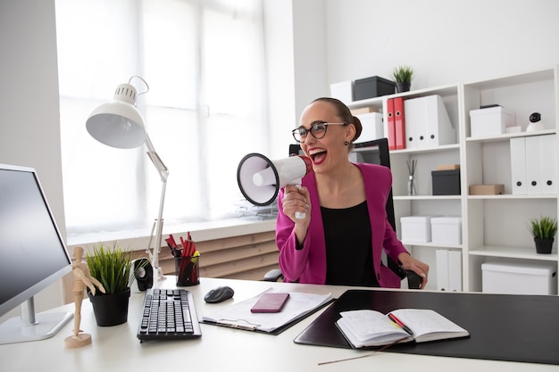 A girl screams into a loudspeaker in the office