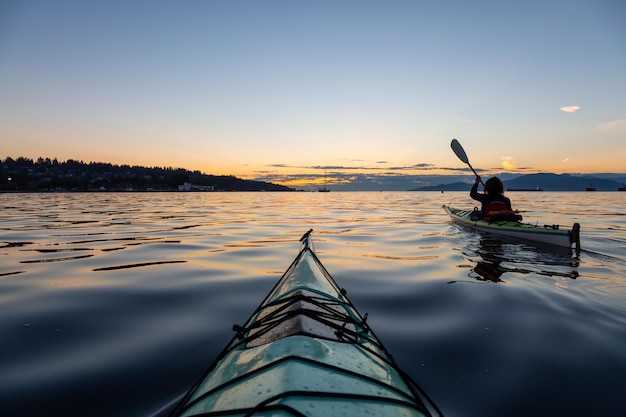 Girl Sea Kayaking during a vibrant sunny summer sunset