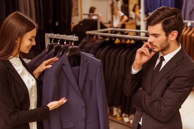 Girl seller helps a man to choose a suit.