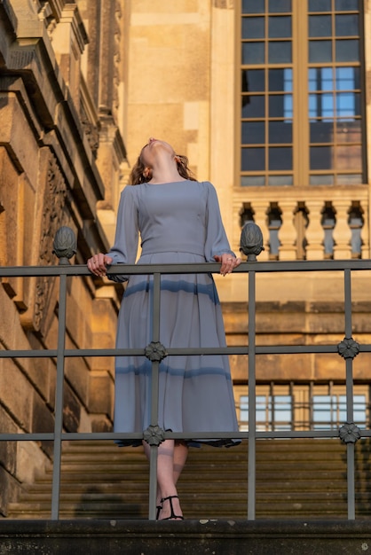 A girl in the setting sun stands on the stairs of the palace Tilt her head back