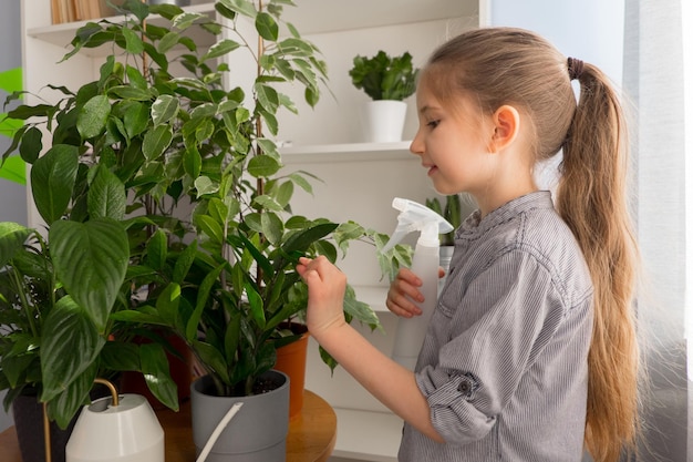 Girl seven years old dressed in shirt looks after sprinkles admires flowers home garden concept