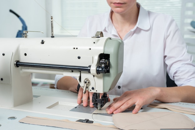 Girl sews on a sewing machine scribbles fabric and leather making a product