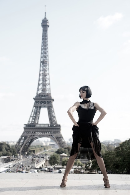 Girl sexy dancer in front of eifel tower in paris, france. beatuiful woman in dance pose like eifel tower. romantic travel concept