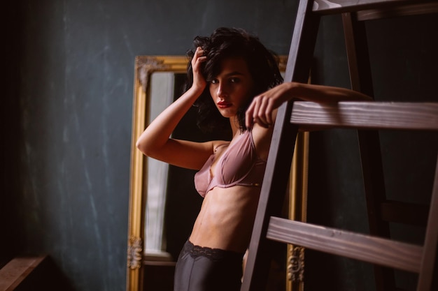 Girl in sexy lingerie with curly black hair posing in vintage interior vintage photo processing