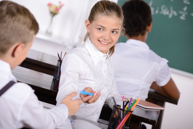 A girl shares a pen with a boy in class.