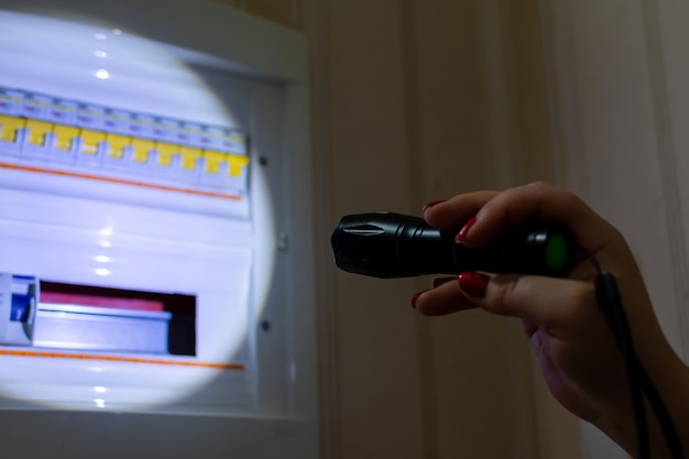 Girl shines a flashlight on a locker with electric fuses