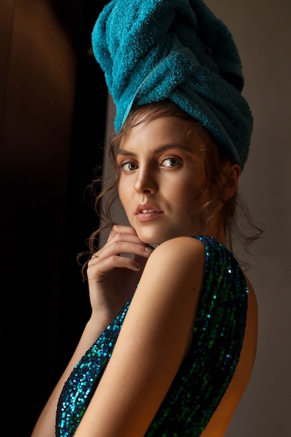 Girl in shiny green-blue dress and towel on head