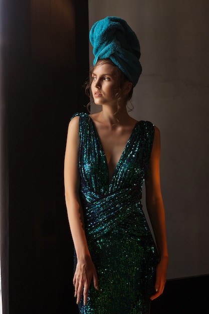 Girl in shiny green-blue dress and towel on head