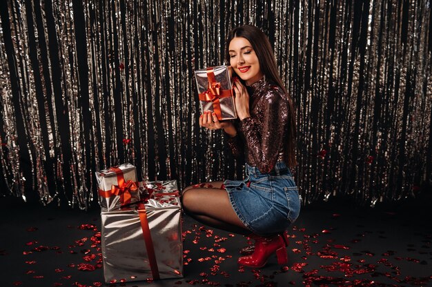 A girl in a shiny jacket and skirt with gifts