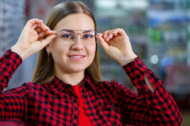 The girl in the shirt takes out and measures on herself glasses