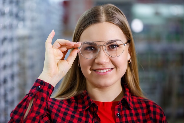 The girl in the shirt takes out and measures on herself glasses