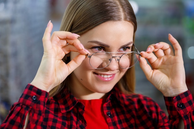 The girl in the shirt takes out and measures on herself glasses