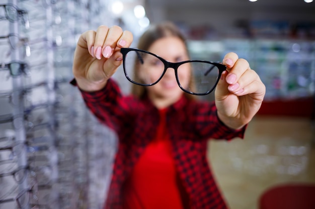 The girl in the shirt takes out and measures on herself glasses