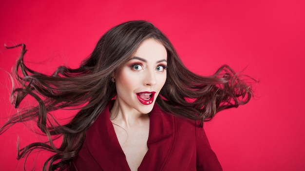 Girl in shock on pink wall. Young beautiful woman with hair up.