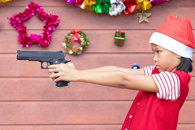 Girl shooting with handgun against christmas decoration