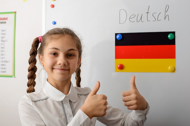 Photo girl showing thumbs up near flag of germany