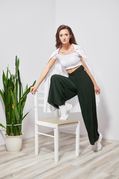 Girl shows on a chair near a green plant