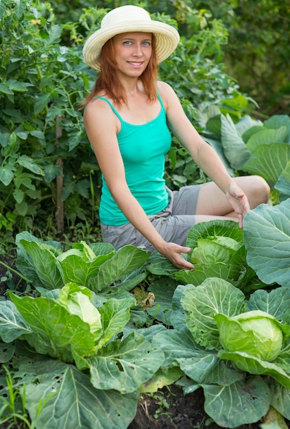 Girl shows a crop of cabbage in the garden