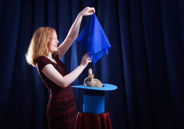 Girl shows focus with a rabbit in a hat